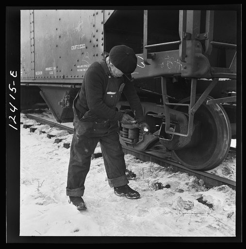 Chicago, Illinois. Workmen inspecting a journal box of a train in a Chicago and Northwestern Railroad departure yard