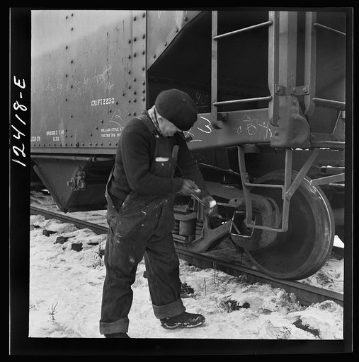 Untitled photo, possibly related to: Chicago, Illinois. Workmen inspecting a journal box of a train in a Chicago and Northwestern Railroad departure yard