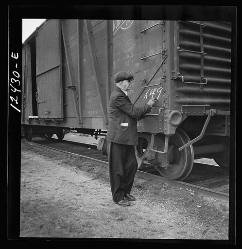 Untitled photo, possibly related to: Chicago, Illinois. Car checker writing instructions in chalk for special handling of cars going over the hump at a Chicago and Northwestern Railroad yard