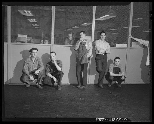 Detroit, Michigan. Assembly of Rolls Royce engines at the Packard motor car company. Workmen smoking cigarettes in an aisle during a five minute recess