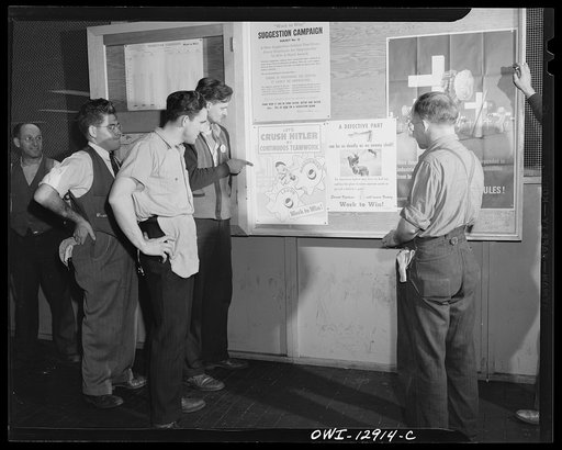 Detroit, Michigan. Assembly of Rolls Royce engines at the Packard motor car company. Workmen inspecting a bulletin board