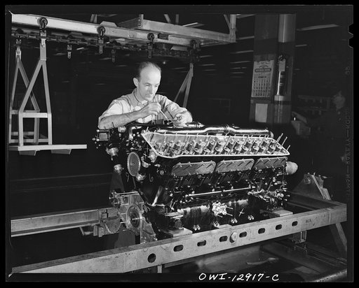 Detroit, Michigan. Assembly of Rolls Royce engines at the Packard motor car company. Installing the primer line in a cylinder bank