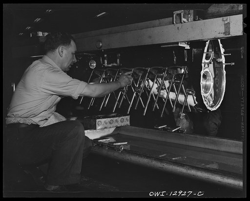 Detroit, Michigan. Assembly of Rolls Royce engines at the Packard motor car company. Putting wire in protectors to prevent rods from damaging the crank case