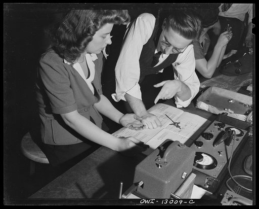 Detroit, Michigan. Assembly of Rolls Royce engines at the Packard Motor Car Company. Foreman explaining method of checking studs to an inspector