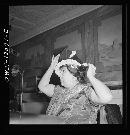 New York, New York. Gypsy woman putting on a paper cap on New Years' Eve in an Italian restaurant on Mulberry Street