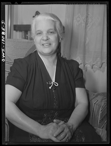 Untitled photo, possibly related to: New York, New York. Mrs. Marianna Costanzo in the living room of her apartment on Waverly Place. Portraits of three sons are on the sideboard, and also a certificate which Ettore got upon graduating from Officer Candidates' School