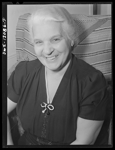 Untitled photo, possibly related to: New York, New York. Mrs. Marianna Costanzo in the living room of her apartment on Waverly Place. Portraits of three sons are on the sideboard, and also a certificate which Ettore got upon graduating from Officer Candidates' School