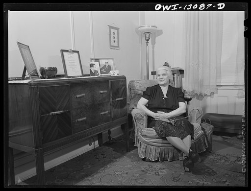 Untitled photo, possibly related to: New York, New York. Mrs. Marianna Costanzo in the living room of her apartment on Waverly Place. Portraits of three sons are on the sideboard, and also a certificate which Ettore got upon graduating from Officer Candidates' School