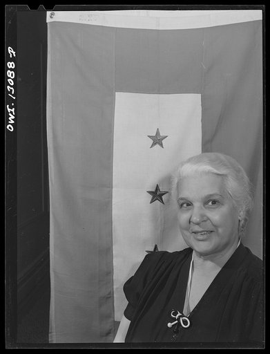 Untitled photo, possibly related to: New York, New York. Mrs. Marianna Costanzo in the living room of her apartment on Waverly Place. Portraits of three sons are on the sideboard, and also a certificate which Ettore got upon graduating from Officer Candidates' School