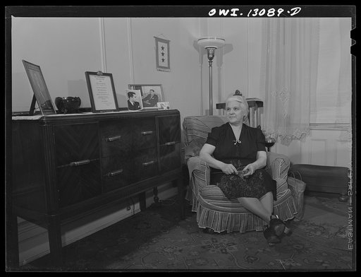 New York, New York. Mrs. Marianna Costanzo in the living room of her apartment on Waverly Place. Portraits of three sons are on the sideboard, and also a certificate which Ettore got upon graduating from Officer Candidates' School