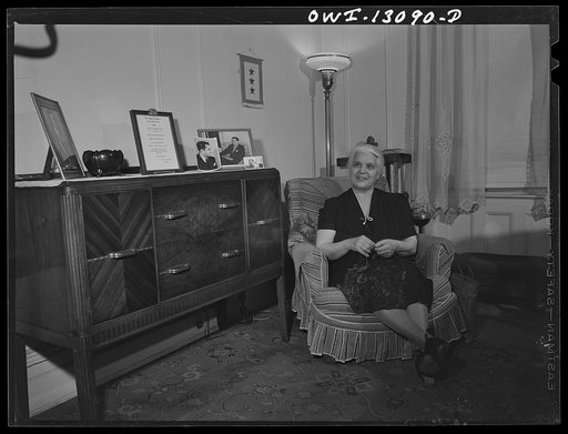 New York, New York. Mrs. Marianna Costanzo in the living room of her apartment on Waverly Place. Portraits of three sons are on the sideboard, and also a certificate which Ettore got upon graduating from Officer Candidates' School