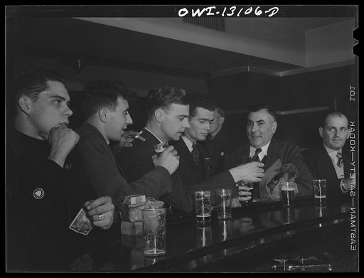 Untitled photo, possibly related to: New York, New York. Merchant seamen's Christmas party at the Andrew Feruseth Club on Christmas Day. The two men on the left in uniform are trainees for the merchant marine. They are opening their Christmas presents, which in two cases turned out to be money belts