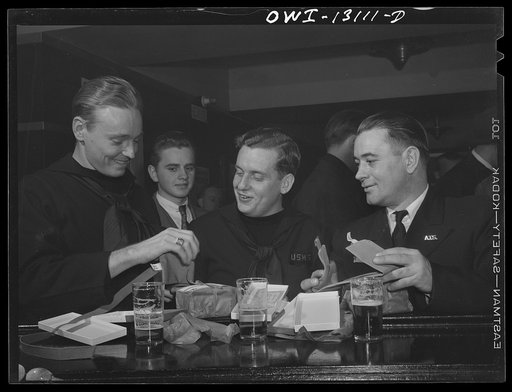 New York, New York. Merchant seamen's Christmas party at the Andrew Feruseth Club on Christmas Day. The two men on the left in uniform are trainees for the merchant marine. They are opening their Christmas presents, which in two cases turned out to be money belts
