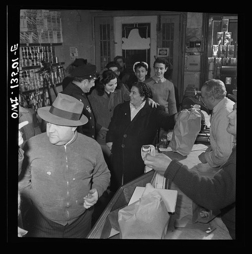 New York, New York. Italian-American policeman chatting with customers in a grocery store on Mulberry Street