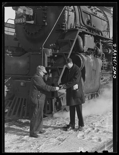 Chicago, Illinois. Conductor handling engineer copy of train orders before a Chicago and Northwestern Railroad freight train pulls out for Clinton, Iowa. Since the track between those points is under automatic train control, the engineer, in turn, hands the conductor the key to the automatic train c