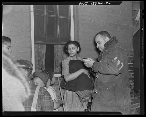 Firehouse Station No. 4. Washington, D.C. A mother holding a small child close to her body to protect him from the cold night. While the mother was away he had turned over a fuel-oil lamp whick set fire to the curtains. This fireman is taking notatations from the mother
