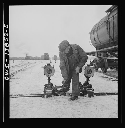 Freight operations on the Indiana Harbor Belt railroad between Chicago, Illinois and Hammond, Indiana. In the background, his train starts to pull out and head-man Lee Hines throws switch to clear the track