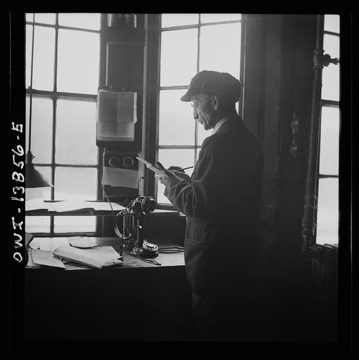 Chicago, Illinois. Yard clerk checking cars as trains are being made up outside his window