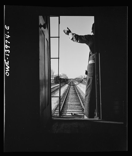 Freight train operations on the Chicago and Northwestern Railroad between Chicago and Clinton, Iowa. Every time a train is passed, the rear brakeman of each train steps out on the caboose platform, and if all is well, as in this case, gives the other brakeman the high sign