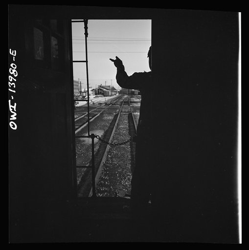 Untitled photo, possibly related to: Freight train operations on the Chicago and Northwestern Railroad between Chicago and Clinton, Iowa. Every time a train is passed, the rear brakeman of each train steps out on the caboose platform, and if all is well, as in this case, gives the other brakeman the