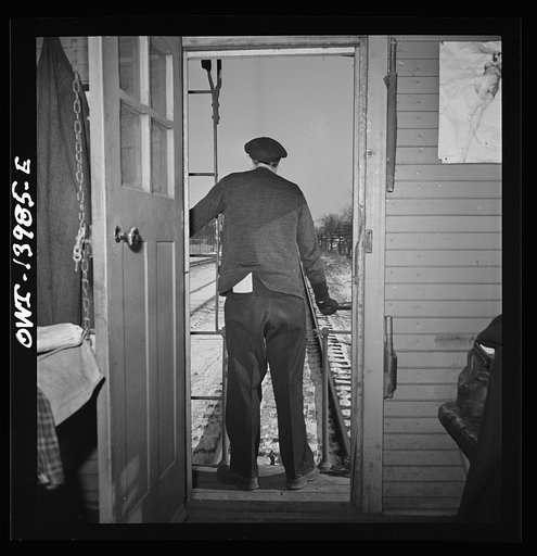 Untitled photo, possibly related to: Freight train operations on the Chicago and Northwestern Railroad between Chicago and Clinton, Iowa. Every time a train is passed, the rear brakeman of each train steps out on the caboose platform, and if all is well, as in this case, gives the other brakeman the
