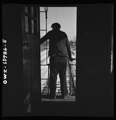 Untitled photo, possibly related to: Freight train operations on the Chicago and Northwestern Railroad between Chicago and Clinton, Iowa. Every time a train is passed, the rear brakeman of each train steps out on the caboose platform, and if all is well, as in this case, gives the other brakeman the