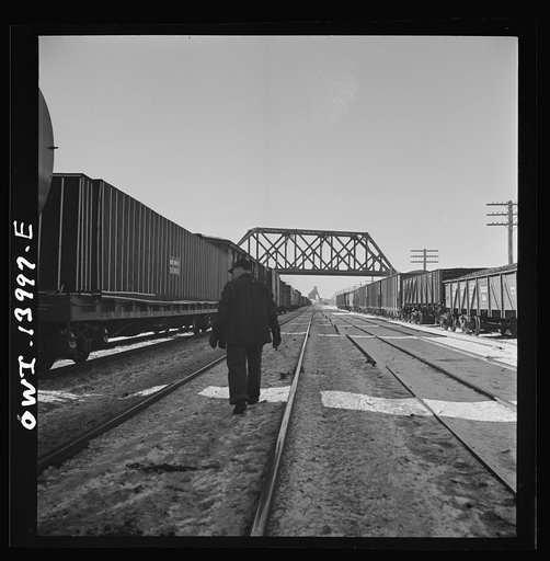 Untitled photo, possibly related to: Freight train operations on the Chicago and Northwestern Railroad between Chicago and Clinton, Iowa. The train stops at DeKalb, Illinois for coal and water. The brakemen make an inspection of the train. Since their time is limited, they walk on the side opposite 