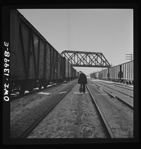 Freight train operations on the Chicago and Northwestern Railroad between Chicago and Clinton, Iowa. The train stops at DeKalb, Illinois for coal and water. The brakemen make an inspection of the train. Since their time is limited, they walk on the side opposite the wind so they smell any hot-boxes 