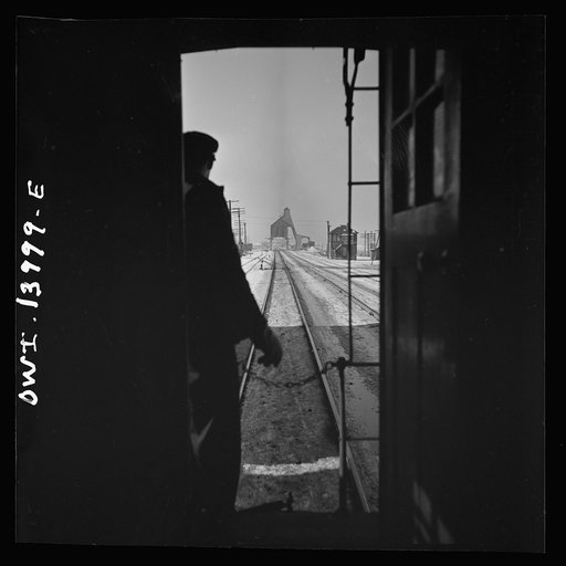 Untitled photo, possibly related to: Freight train operations on the Chicago and Northwestern Railroad between Chicago and Clinton, Iowa. As the train goes through a small town, the conductor exchanges high signs with a switch tender