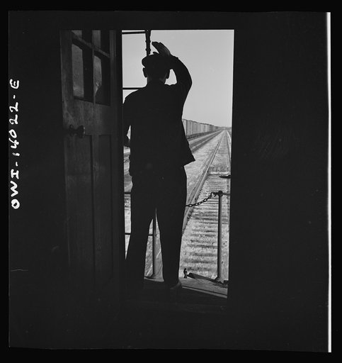 Untitled photo, possibly related to: Freight train operations on the Chicago and Northwestern Railroad between Chicago and Clinton, Iowa. As the train goes through a small town, the conductor exchanges high signs with a switch tender