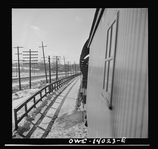 Untitled photo, possibly related to: Freight train operations on the Chicago and Northwestern Railroad between Chicago and Clinton, Iowa. The rear brakeman hops on as the train starts again after waiting for a passenger train to go by