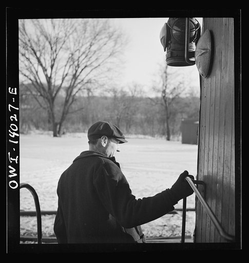 Untitled photo, possibly related to: Freight train operations on the Chicago and Northwestern Railroad between Chicago and Clinton, Iowa. The conductor standing on the caboose platform ready to hop off as the train passes the yard office at the end of the trip