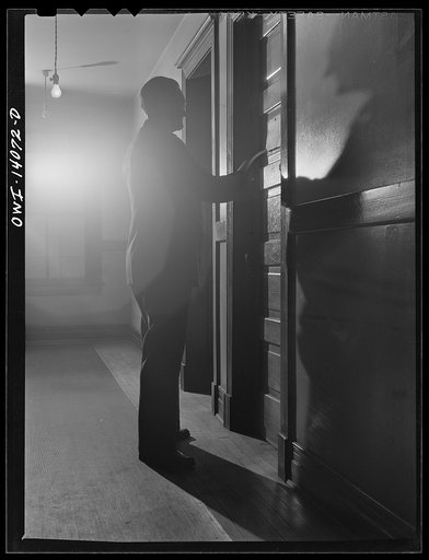 Untitled photo, possibly related to: Gibson, Indiana. Railroad workers go to work at all hours of the day and night. The clerk at the desk of the railroad YMCA (Young Men's Christian Association) knows when each man is due for work and here he is waking a man early in the afternoon