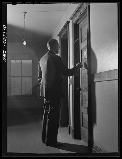 Gibson, Indiana. Railroad workers go to work at all hours of the day and night. The clerk at the desk of the railroad YMCA (Young Men's Christian Association) knows when each man is due for work and here he is waking a man early in the afternoon