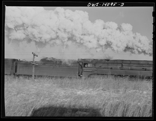 Untitled photo, possibly related to: Brakeman standing with a flag, waiting for a Chicago and Northwestern Railroad fast passenger train to go by so that his train can get on the main line in Illinois
