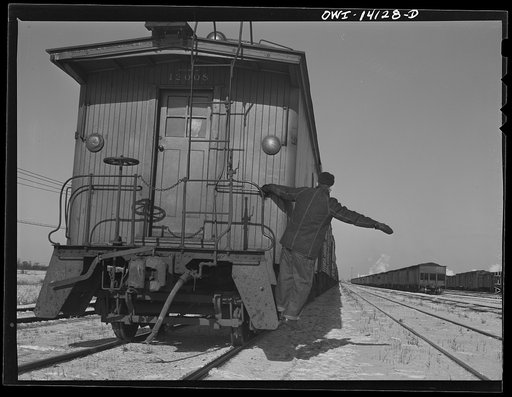 Rear brakeman gets on the caboose and signals engineer that all's well at the rear end of the Chicago and Northwestern Railroad freight train