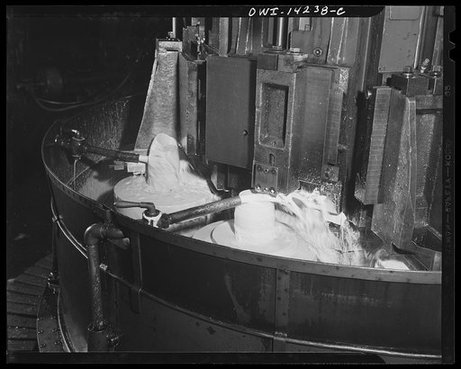 Detroit, Michigan. Steps in the manufacture of casings for 105 mm. shells in the Budd wheel plant. Lubricating fluid pouring on the base end of a shell which is being finished