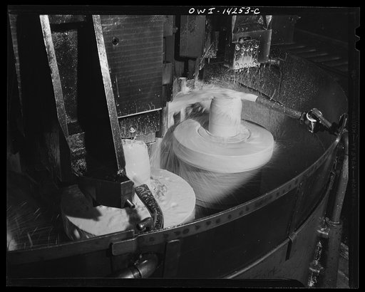 Untitled photo, possibly related to: Detroit, Michigan. Steps in the manufacture of casings for 105 mm. shells in the Budd wheel plant. Lubricating fluid pouring on the base end of a shell which is being finished