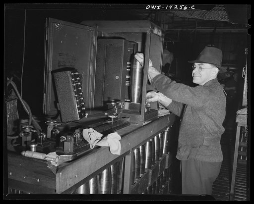 Detroit, Michigan. Steps in the manufacture of casings for 105 mm. shells in the Budd wheel plant. United States ordinance inspector, inspecting a shell in the electrical measuring machine