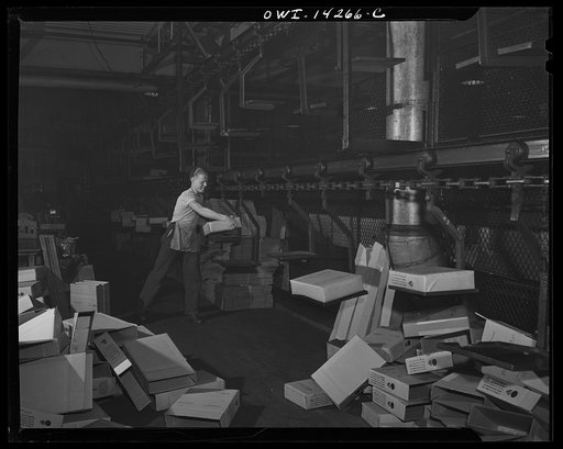 Detroit, Michigan. Steps in the maufacture of casings for 105 mm. shells in the Budd wheel plant. Placing carton of shells on the conveyor line