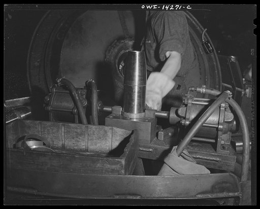 Detroit, Michigan. Steps in the maufacture of casings for 105 mm. shells in the Budd wheel plant. Applying the rotating band of the gilding metal. Gilding metal is a combination of copper and zinc