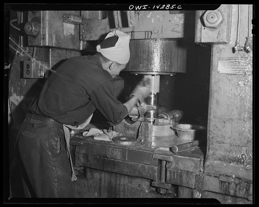 Detroit, Michigan. Steps in the manufacture of casings for 105 mm. shells in the Budd wheel plant. Painting on lubricating fluid before cold nosing a rough turned shell. Cold nosing is a process of squeezing the end of a shell together by tremendous pressure
