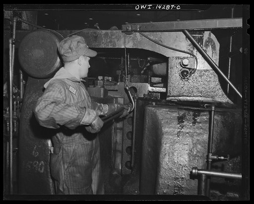 Detroit, Michigan. Steps in the manufacture of casings for 105 mm. shells in the Budd wheel plant. Squeezing the red end of the bar between the jaws of a giant press containing dies of different sizes