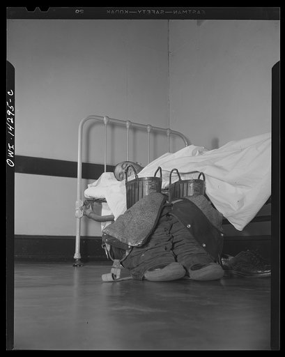 Firehouse station number four. Washington, D.C. A young fireman sleeps in his shirt and socks. When the alarm goes off he steps quickly into his boots that have pants attached complete with suspenders, adjusts them on the run, and slides down the pole to the truck he will ride to the fire