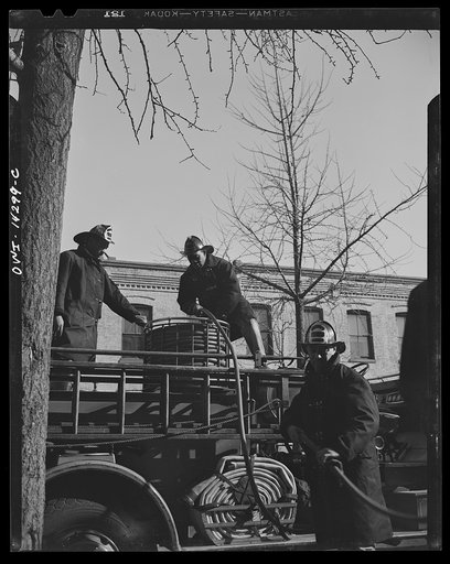 Firehouse station number four. Washington, D.C. Firemen retrieving a small hose after extinguishing a blaze. The young firemen in the foreground took his first ride