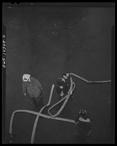 Firehouse station number four. Washington, D.C. Firemen preparing to mount a ladder with a large hose during a fire