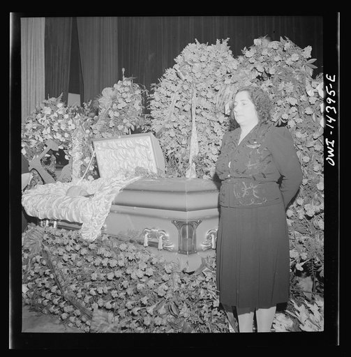 New York, New York. Woman wearing a one-star pin showing that she has a son in the United States Armed Services, guarding the coffin containing the body of murdered Carlo Tresca as mourners pass by to pay their respects