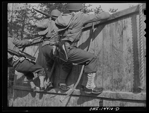 Untitled photo, possibly related to: Fort Belvoir, Virginia. Privates Chirico and Dalto and Sergeant Tauro scaling a fence on the obstacle course