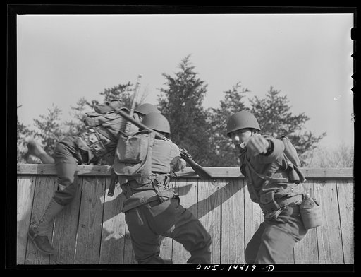 Untitled photo, possibly related to: Fort Belvoir, Virginia. Privates Chirico and Dalto and Sergeant Tauro scaling a fence on the obstacle course