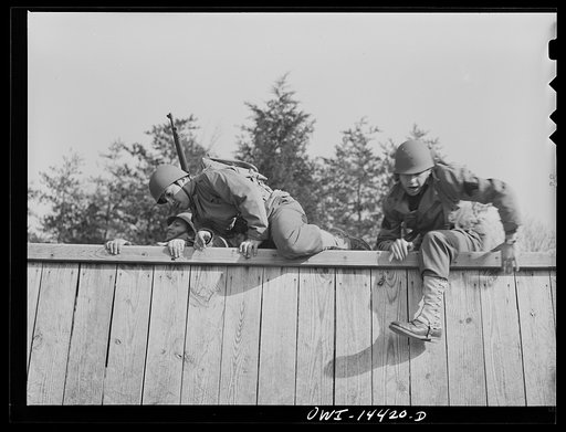 Untitled photo, possibly related to: Fort Belvoir, Virginia. Privates Chirico and Dalto and Sergeant Tauro scaling a fence on the obstacle course